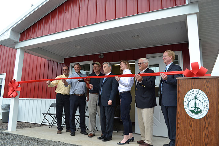 A group of people cuts a red ribbon to celebrate the opening of the swine science center. 