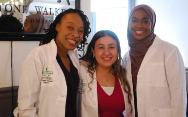 Physician assistant students in white coats pose for a photo.