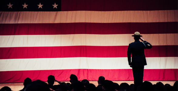 A veteran stands in front of an american flag.