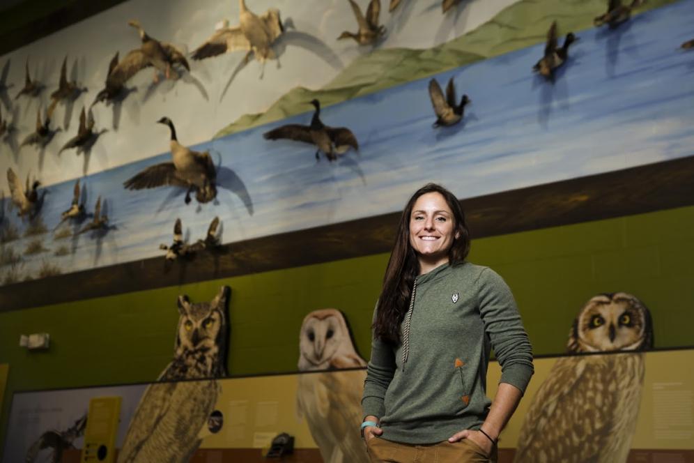 Lauren Fenstermacher, a DelVal alumna, poses for a photograph in front of a wall with birds at Middle Creek Wildlife Management Area.