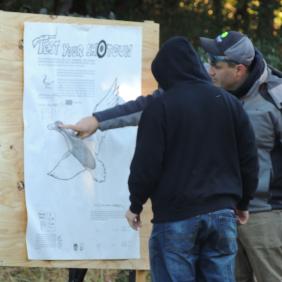 A conservation wildlife officer pointing to a goose poster with a student