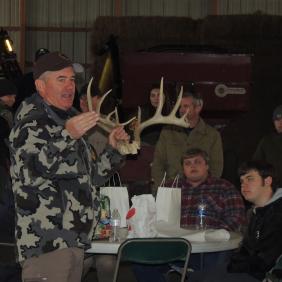 A man holds up deer antlers to a group of students