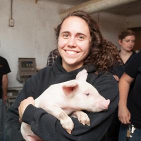 Female student holding a pink pig