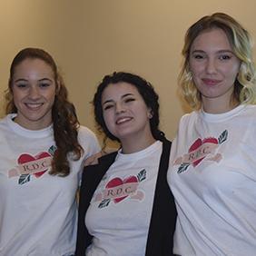 Three students standing together wearing shirts that have their business logo on the front.