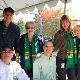 Six elderly DelVal alumni are posed for a photo at the homecoming tent. 