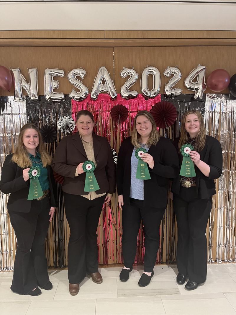 Team A: 5th Place, a group of four women in professional attire holding up green ribbons.