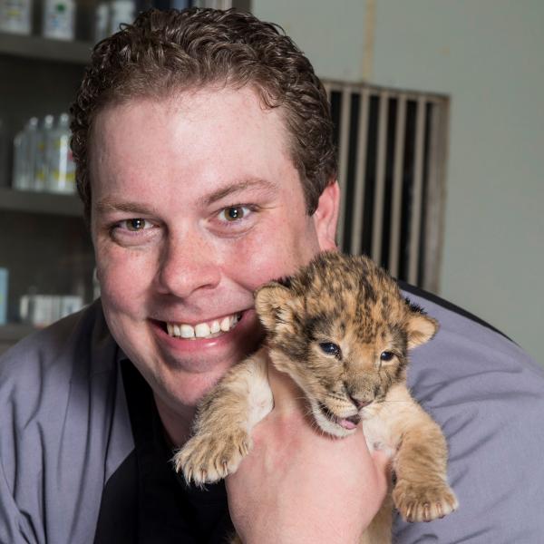 A student holds a lion cub