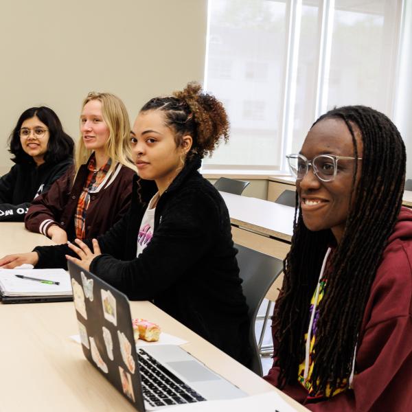 Students are sitting in class with their laptops open.