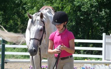 a girl in riding gear leading a white horse