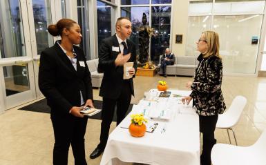 Two spark bowl participants dressed in suit and ties speak to a DelVal staff member.