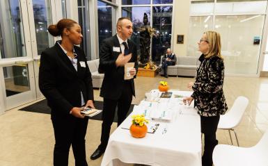 Two spark bowl participants dressed in suit and ties speak to a DelVal staff member. 