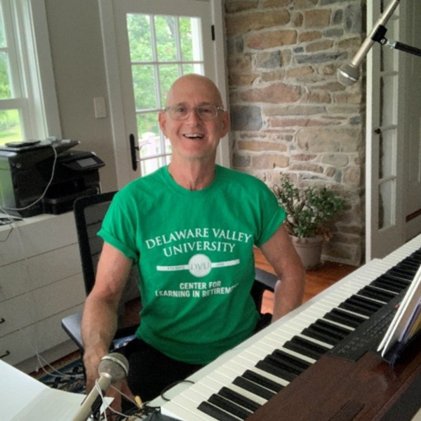 A CLR member is in front of a piano and microphone for a music making course.