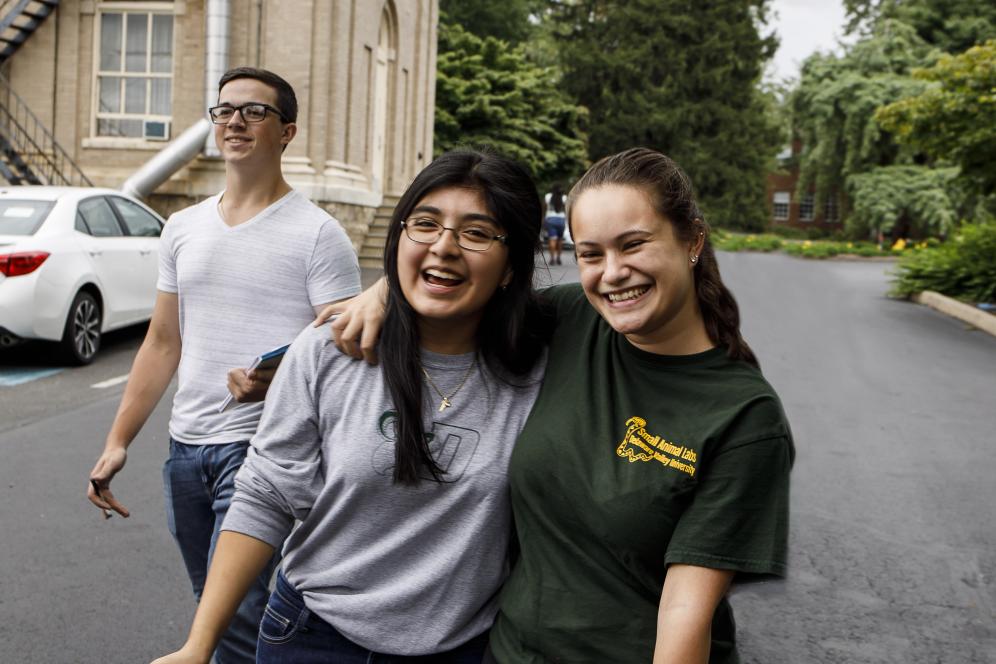 Two students who are holding papers walk to a workshop on career preparation at Delaware Valley University.