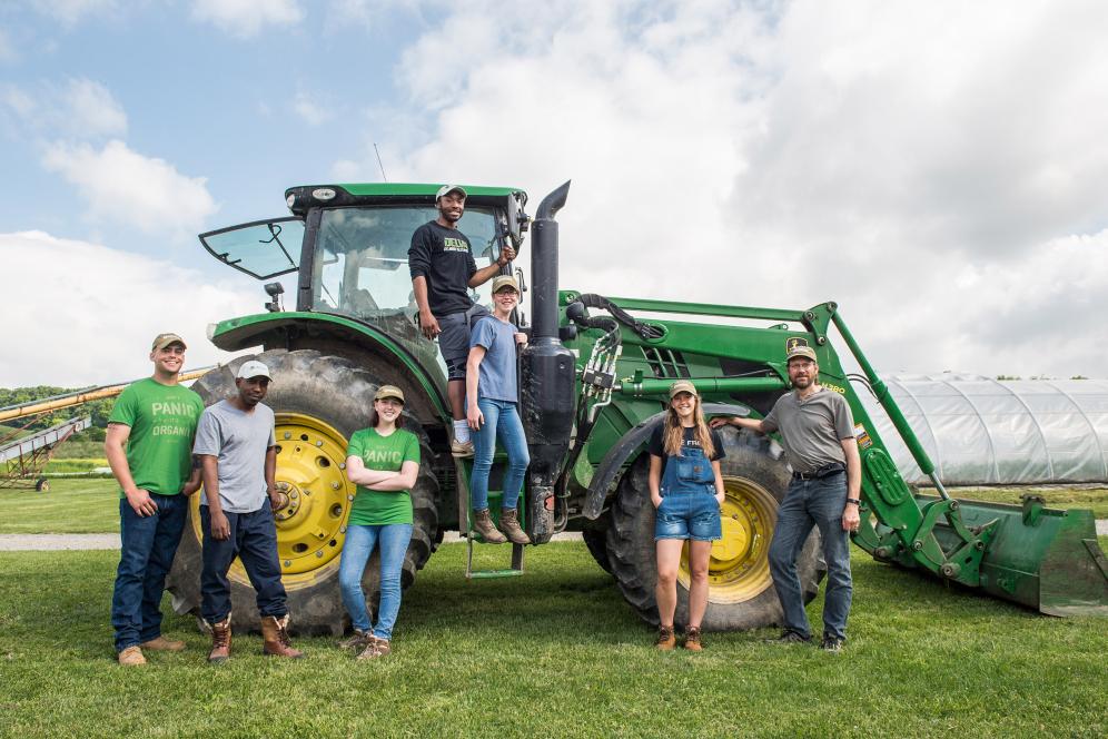 group of students posing on and with a tractor