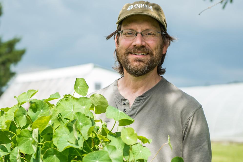 male student holding plant in the fields