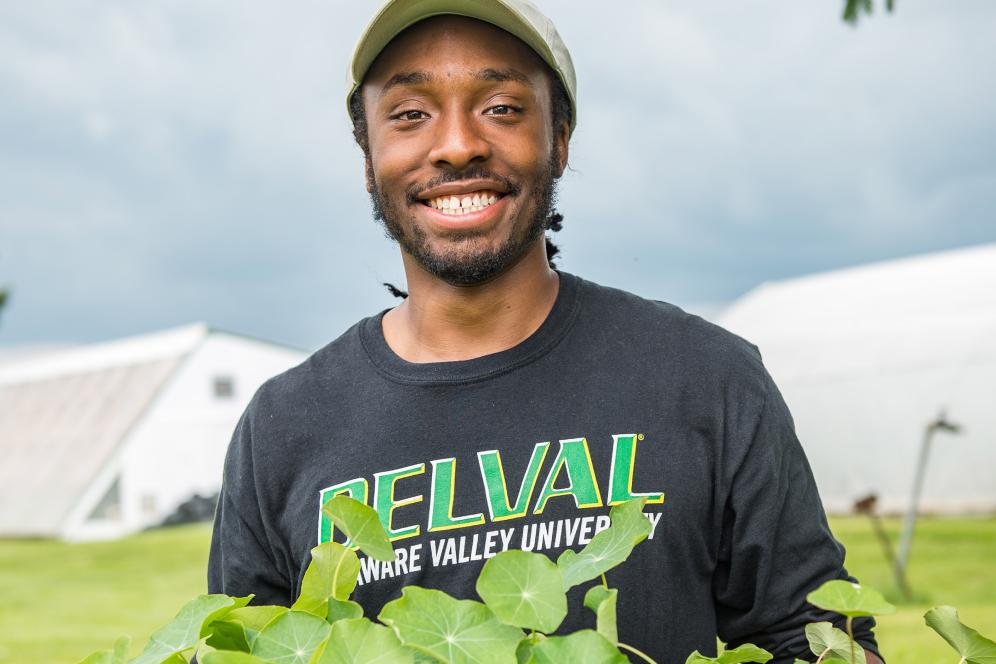 male student holding plant in the fields