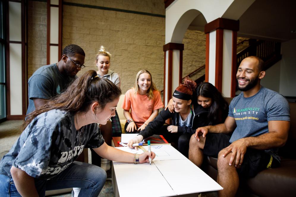 A group of students gathered around a posterboard writing.