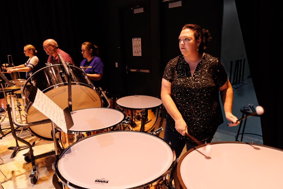 Professor Jessica McCall is drumming on stage.