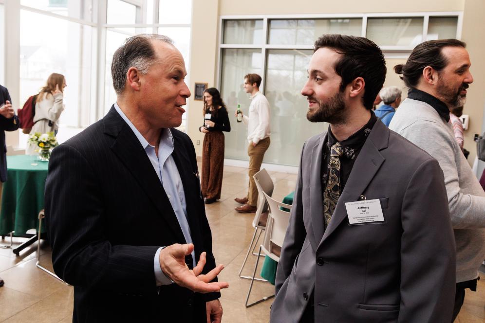 A student is with a scholarship donor. They are talking in the life sciences building.
