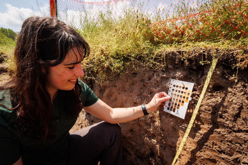 Jaclyn Fiola inside a soil pit with a tape measure.