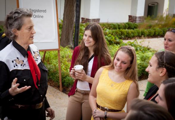 Dr. Temple Grandin stands outside talking with DVU students. 