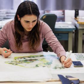 Landscape Architecture students working with markers on a large printed project.