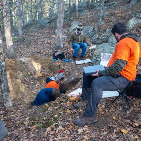 Students are in a soil pit, analyzing soil samples.