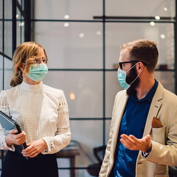 Two hospital administrators speaking in a hallway, both wearing protective masks.