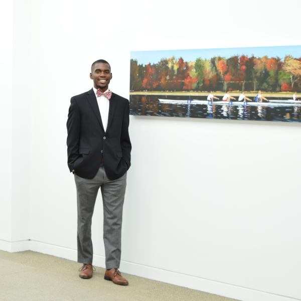 A business student standing next to a painting on the wall.