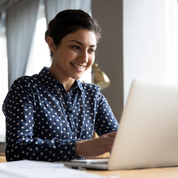Young woman smiling looking at a laptop.