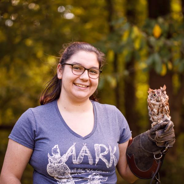A female student is holding an owl at AARK wildlife rehabilitation center.