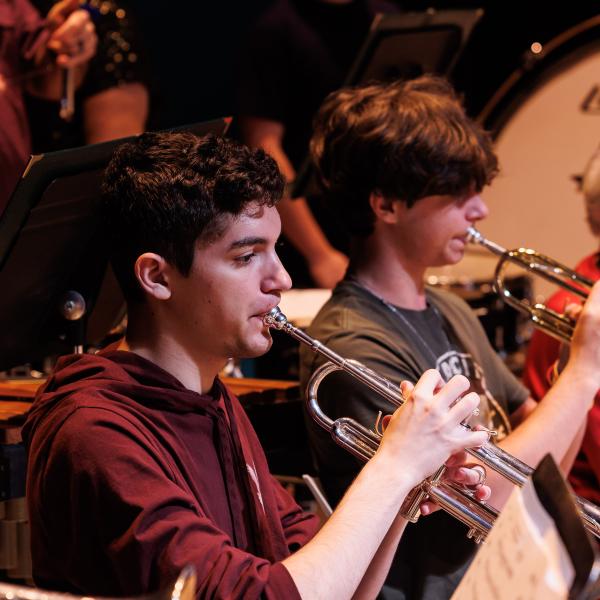 Students playing a horn as part of the symphonic band.