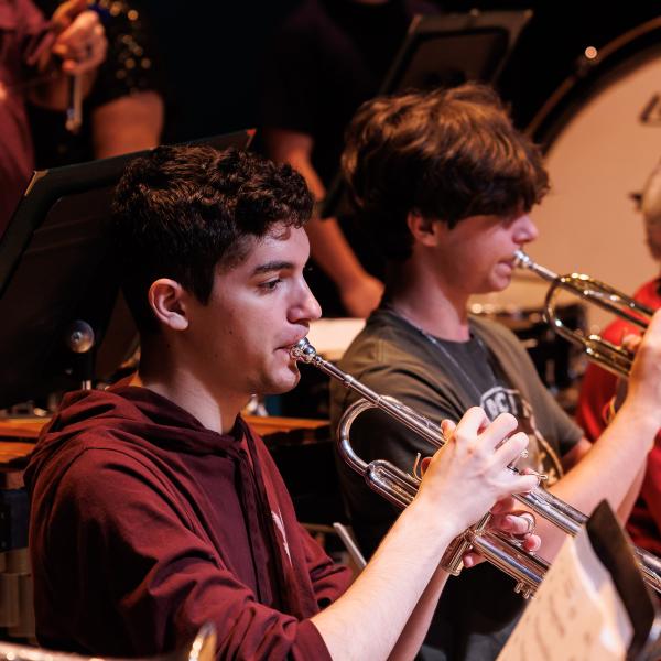 Students playing a horn as part of the symphonic band. 