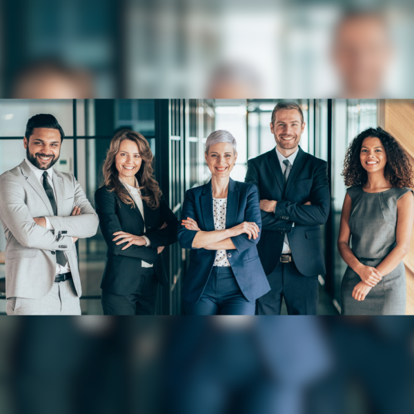 A group of graduate students are standing in business attire side by side.