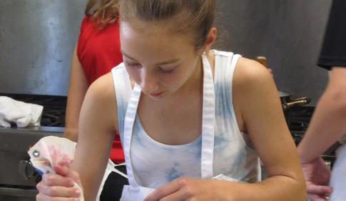 A young girl works with a piping bag.