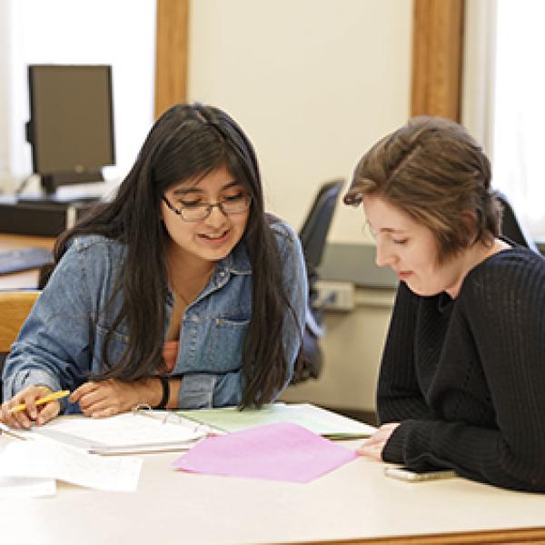 Two students working together with papers in front of them.